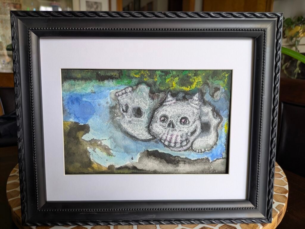Three ghoulish skulls float above a dark black crater in the rocky ground. One skull upside down, one skull with a cheshire grin & horns and the last a skull mask. The background has blotches of green & yellow clouds with a blue sky.